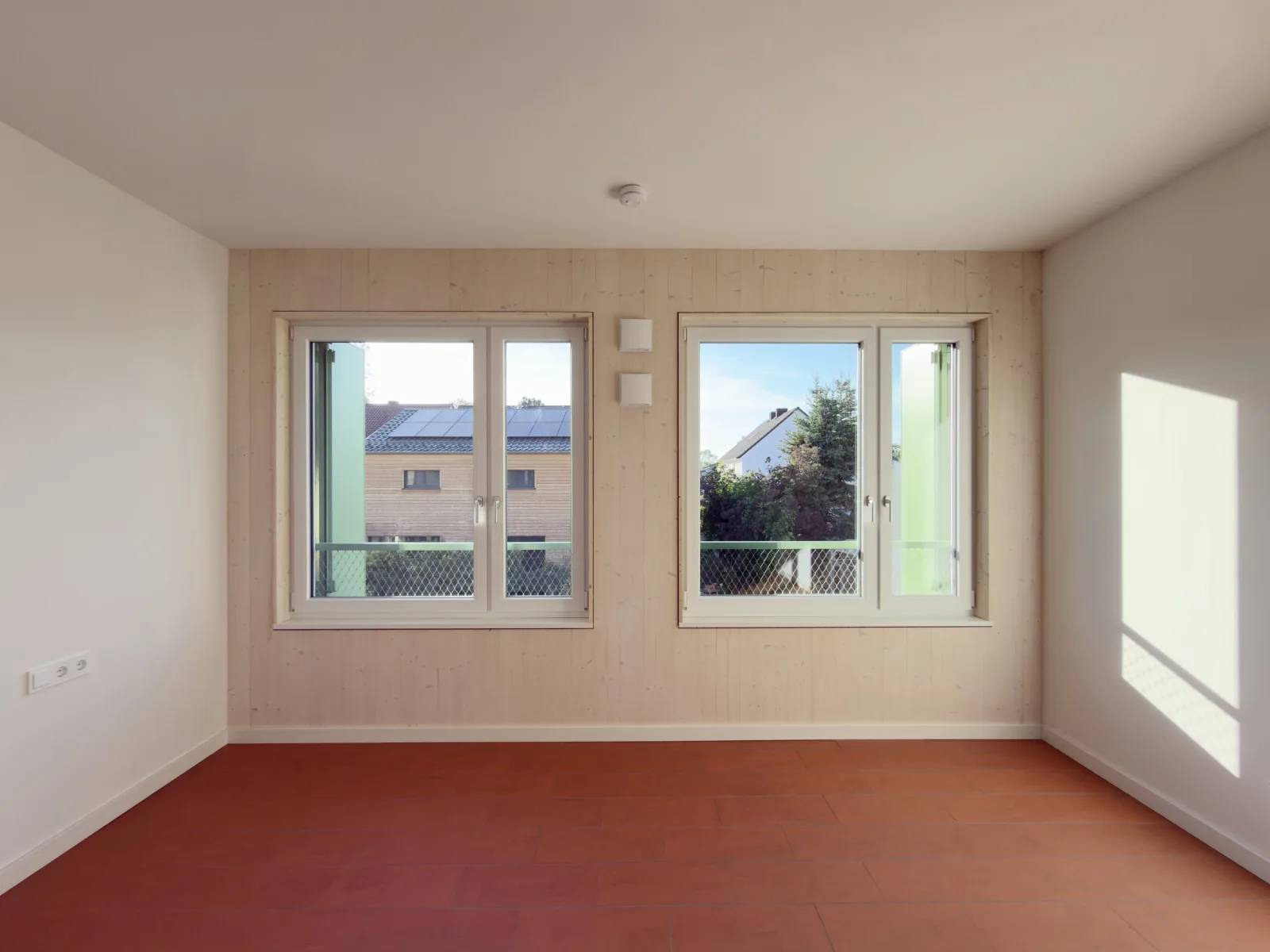 Innenraum mit roten Fliesen und Blick nach draußen durch zwei Fenster